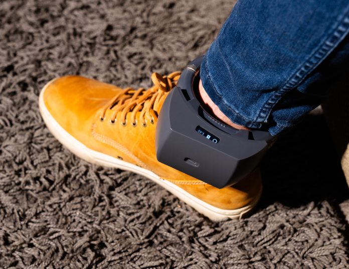 Individual in shoes featuring a compact device on their foot, highlighting advancements in footwear design.