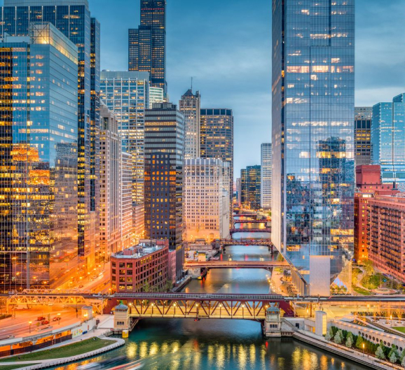 The Chicago River flows gently as the city skyline glows at dusk, showcasing a blend of architectural beauty and twilight colors.